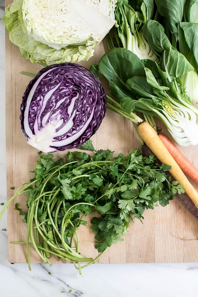 cabbage, bok choy, carrots, cilantro on cutting board