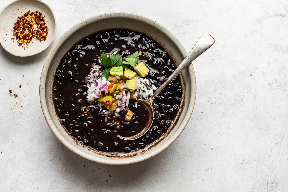 bowl of cuban-style black bean soup served with toppings