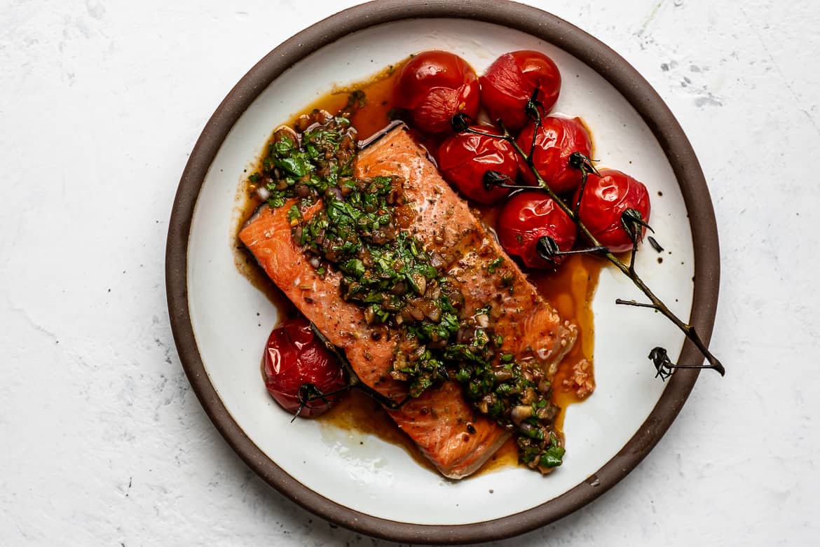 Baked Salmon with Red Chimichurri sauce served on plate with cherry tomatoes