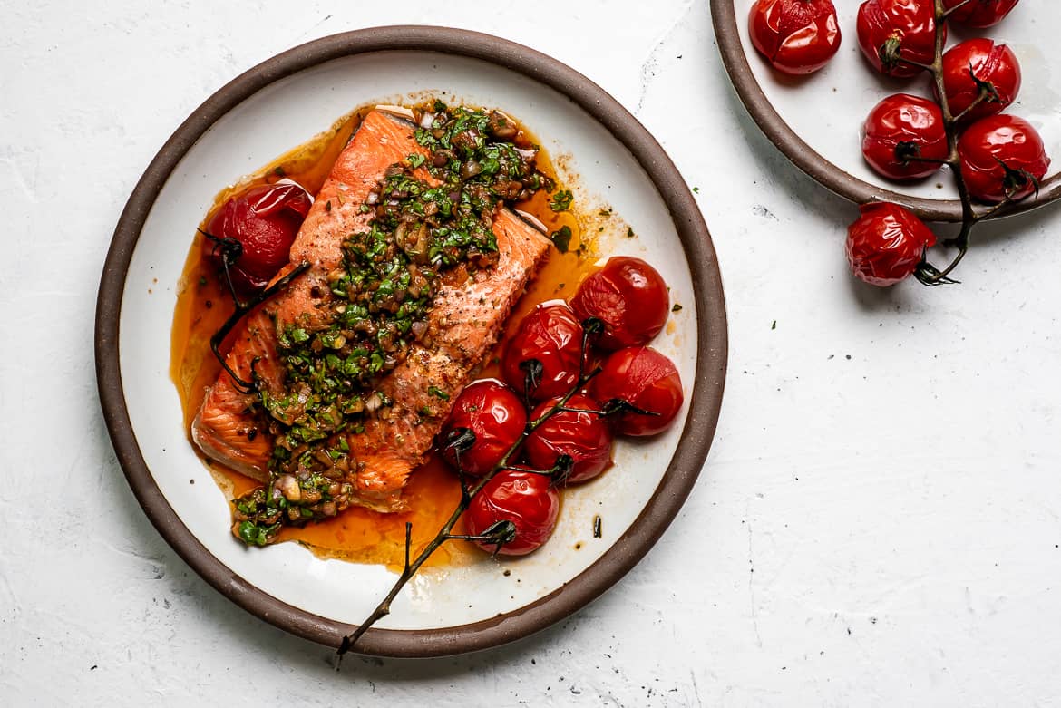 Baked Salmon topped with red chimichurri sauce and baked cherry tomatoes on the side