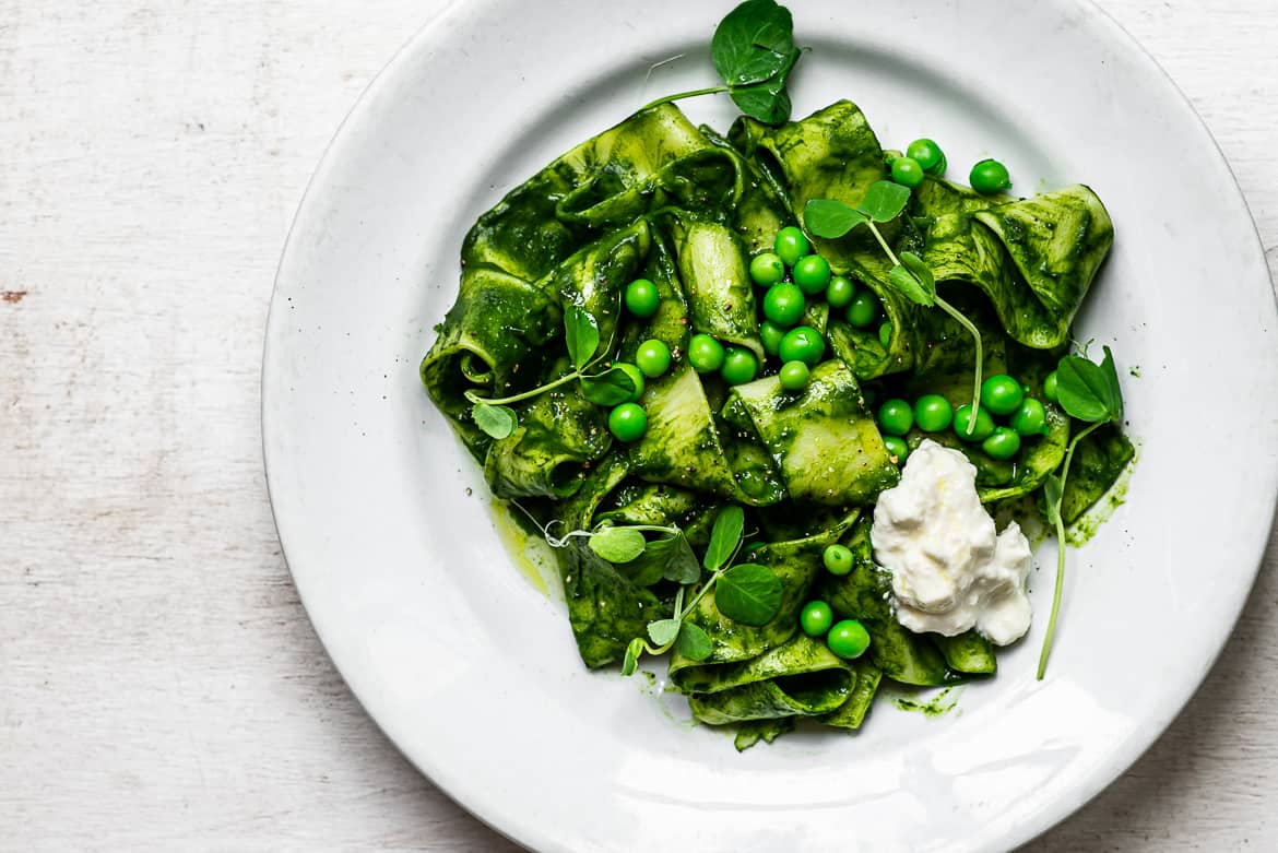 Pasta with kale sauce, peas and burrata on plate 