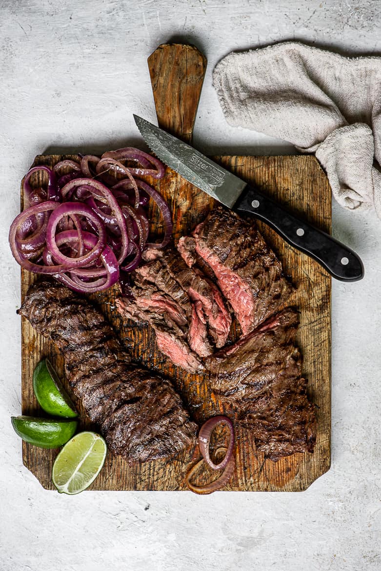 Grilled Skirt Steak Encebollado - steak with onions on cutting board