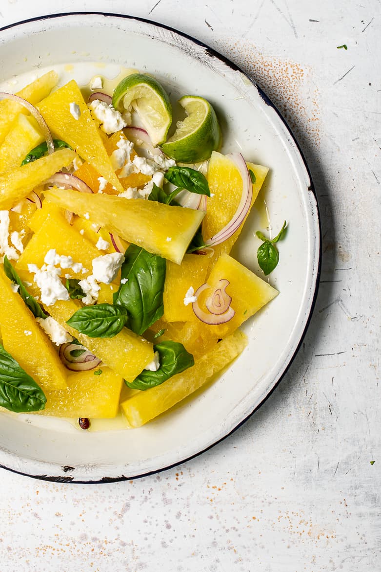 Yellow watermelon and feta salad with red onion and basil on plate