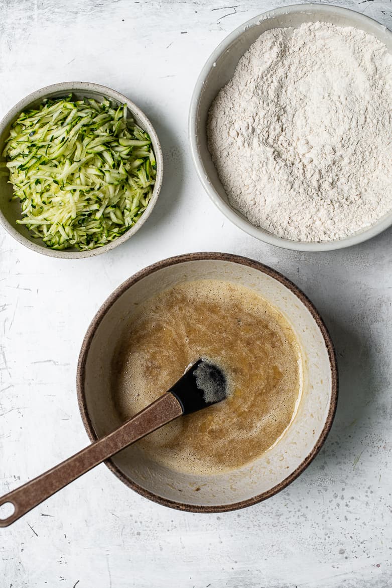 Bowl with grated zucchini, bowl with flour, bowl with mashed bananas