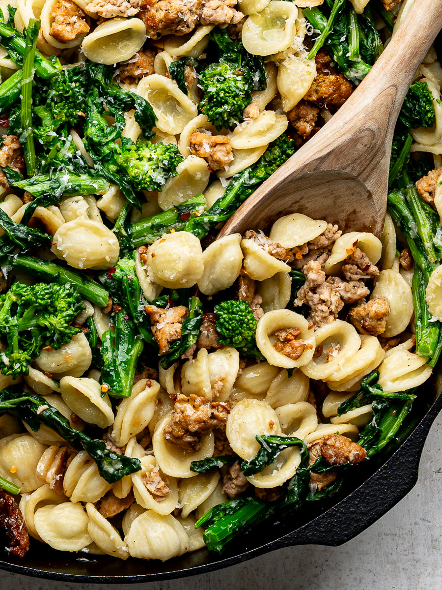 Close-up of orecchiette with rapini and sausage in skillet.