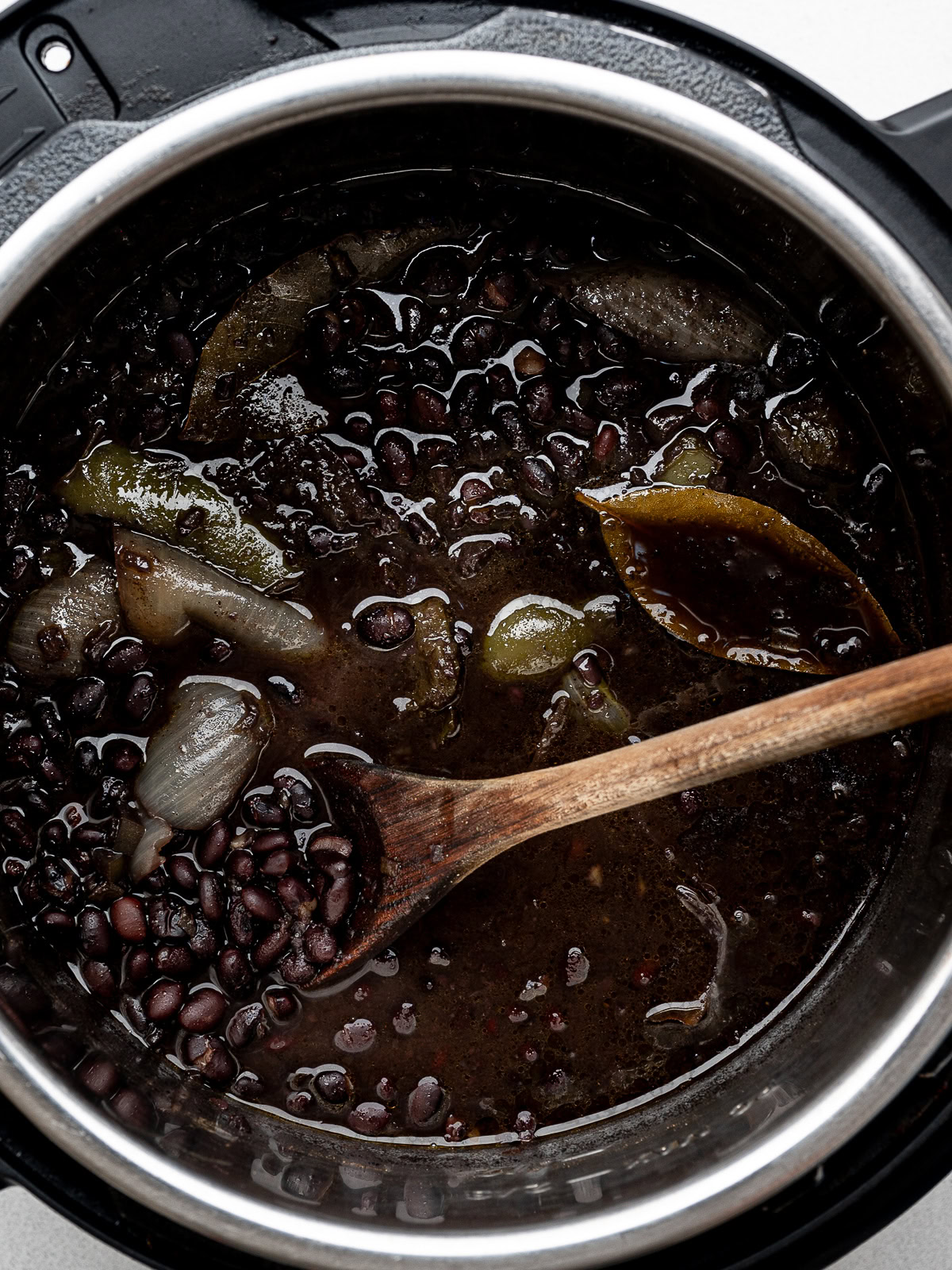 cooked beans in the Instant Pot with a wooden spoon scooping some out