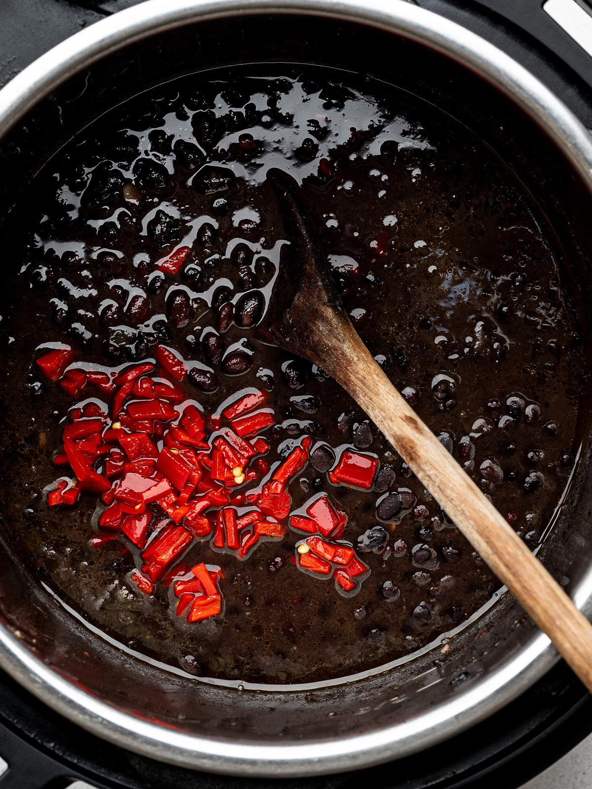 closeup of cooked beans in the instant pot with jarred roasted peppers added