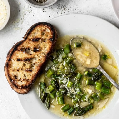 Asparagus and rice soup served in bowl with crusty bread