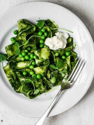 kale sauce pasta with Peas and Burrata cheese on plate with fork