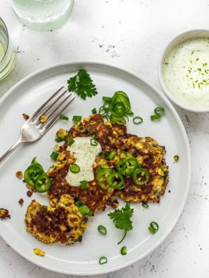 Corn and Poblano fritters on plate with cilantro yogurt sauce and drinks