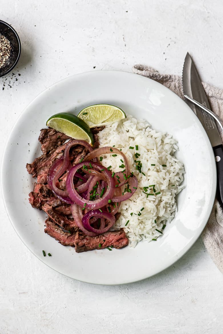 Grilled Skirt Steak Encebollado - steak with onions and rice on plate