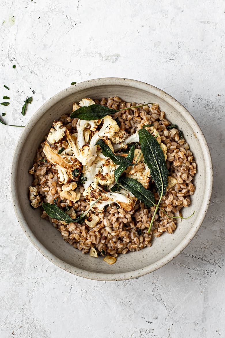 Farrotto in bowl topped with cauliflower and sage