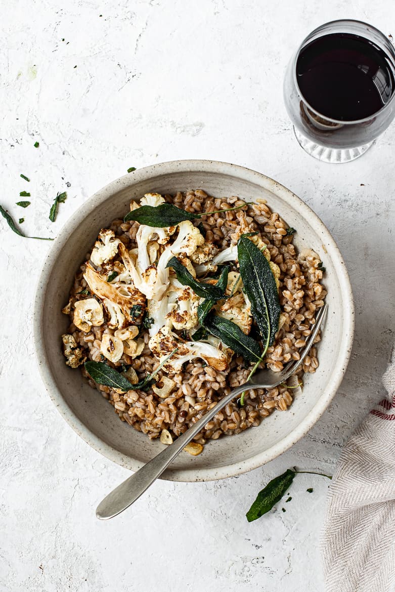 Farro risotto in bowl with cauliflower and glass of red wine