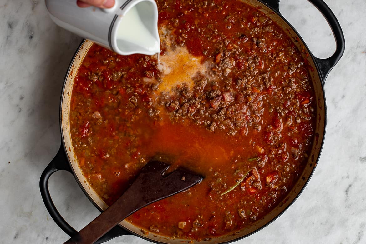 Pouring milk into Bolognese sauce