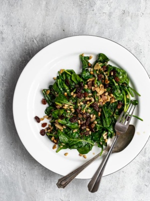 Spinach with raisins and pine nuts served on a platter