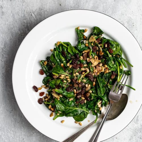 Spinach with raisins and pine nuts served on a platter