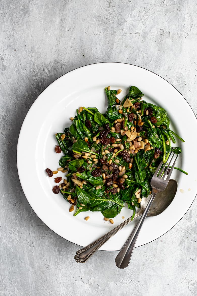 Spinach with raisins and pine nuts served on a platter