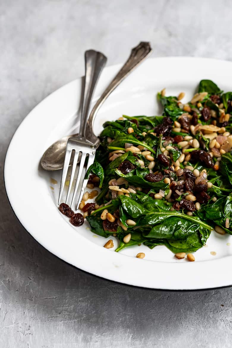 Side view of Sautéed spinach, raisins and pine nuts on platter 