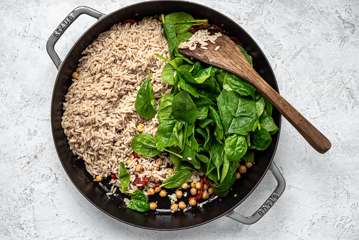 adding orzo and spinach to skillet