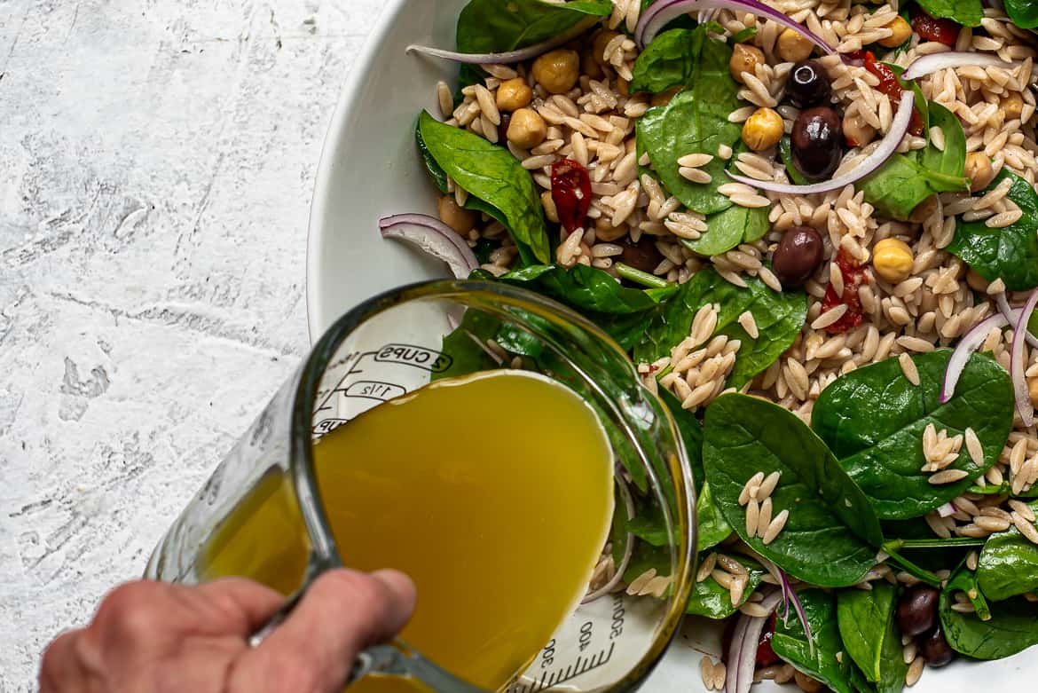 Pouring dressing on orzo salad