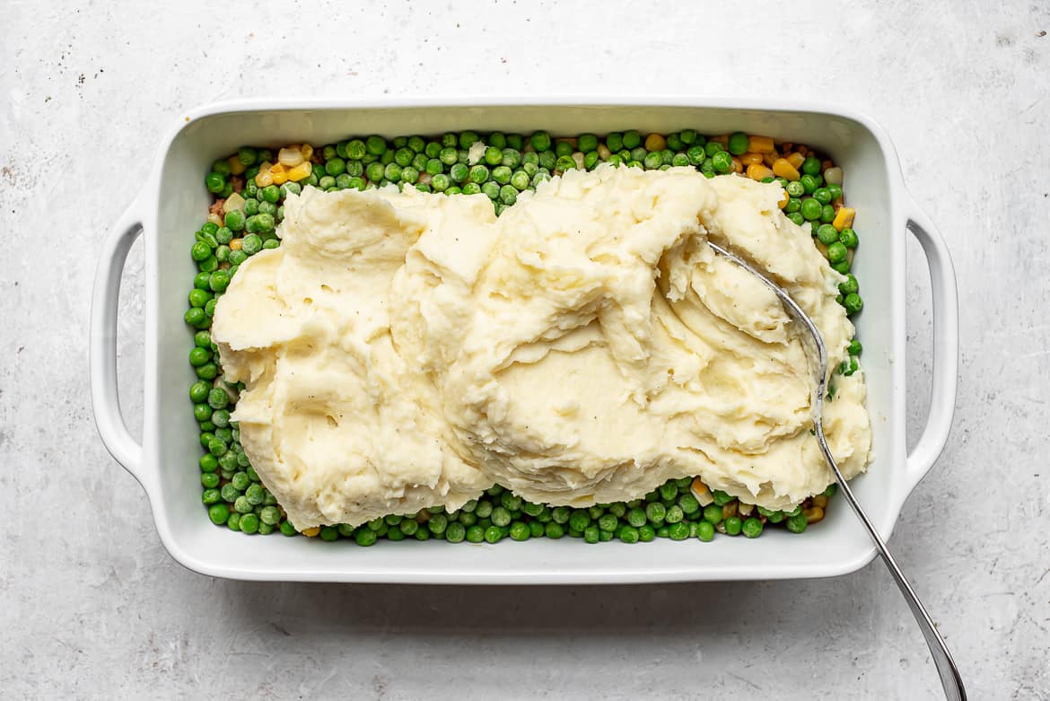 spreading mashed potatoes over turkey mixture