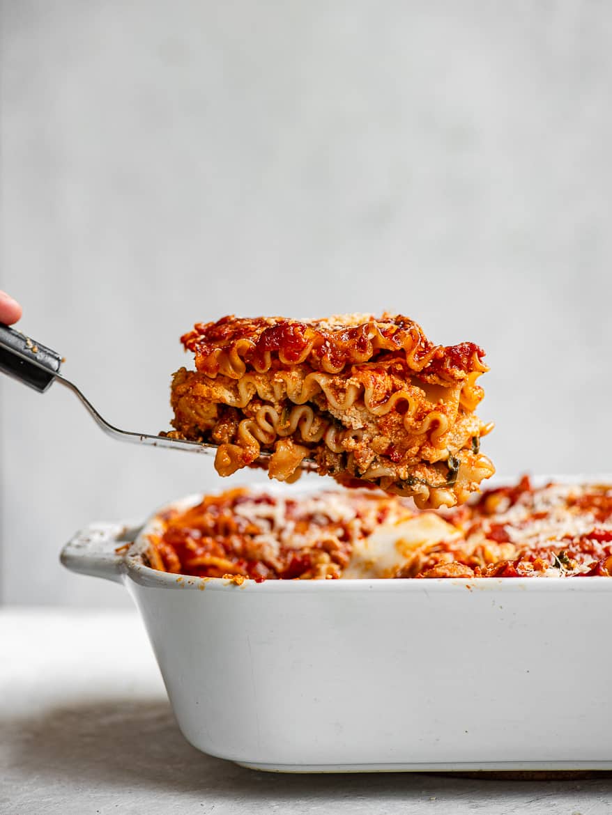 Side view of lasagna being lifted out of baking dish
