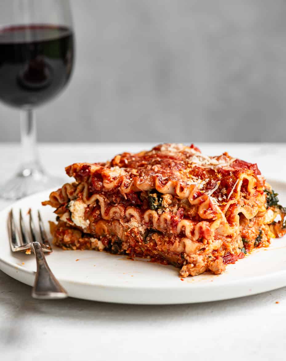 lasagna served on plate with glass of wine