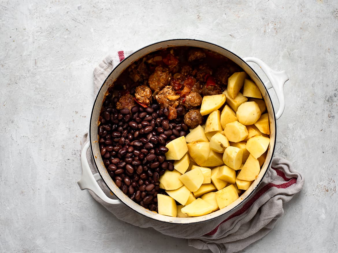 Diced potatoes and black beans in pot with sausage