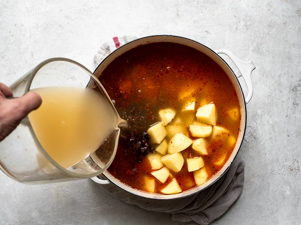 Adding broth to the vegetables and chorizo