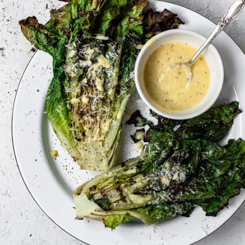 Grilled Romaine hearts on platter with caesar dressing
