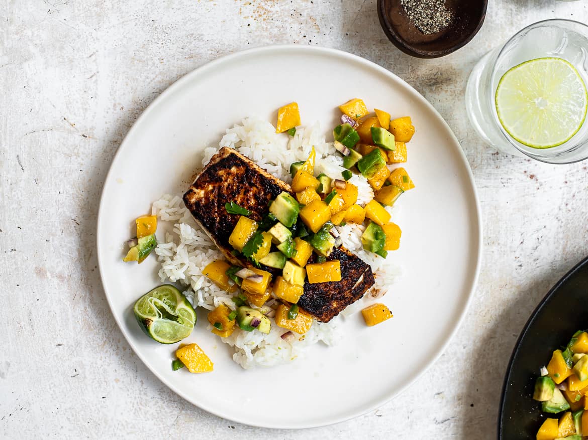 cooked fish with mango salsa and rice on plate