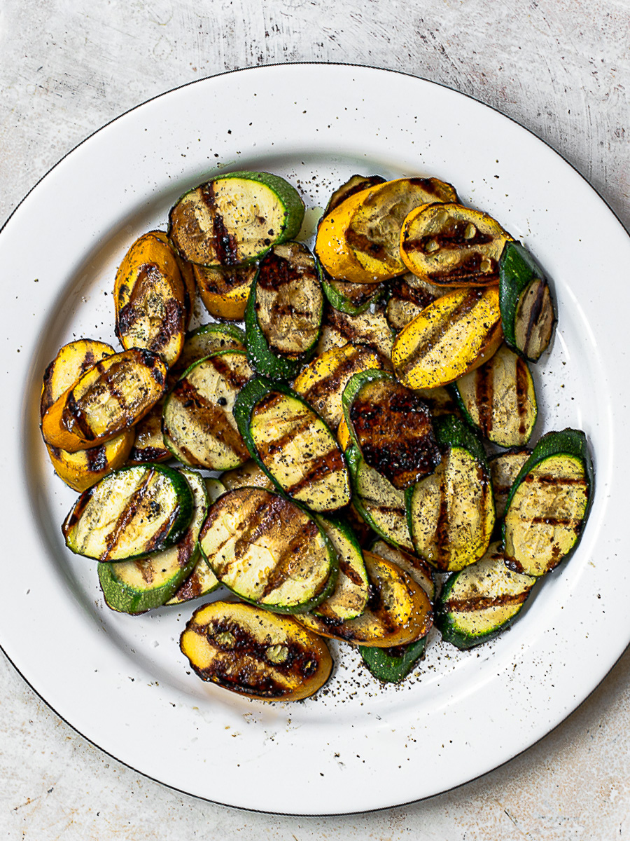 Grilled slices of Zucchini and yellow squash in white bowl. 