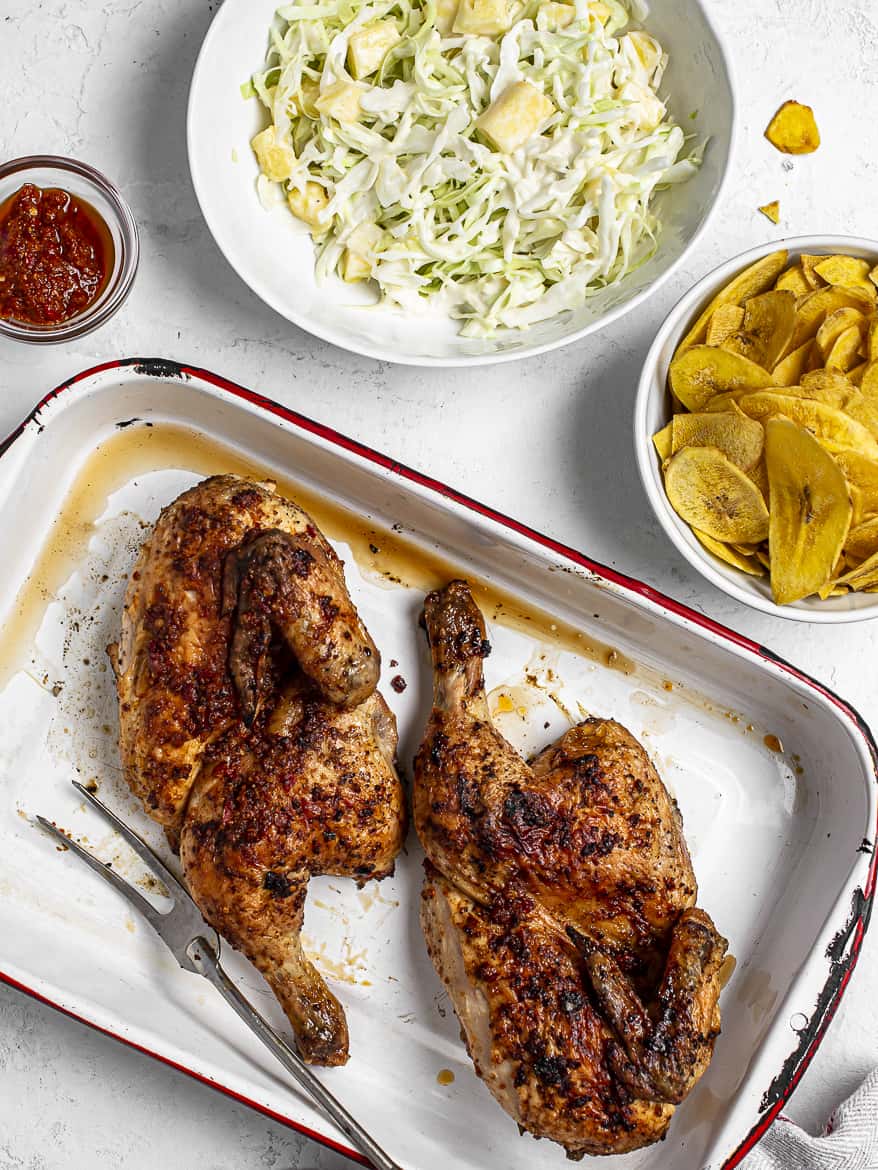 Grilled Piri piri chicken in metal tray with side of cole slaw and plantain chips