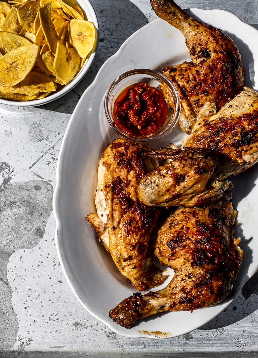 Piri piri chicken on platter with bowl of plantain chips