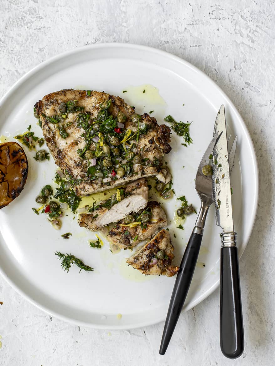 Perfectly grilled juicy chicken breast with Italian Salsa verde on plate