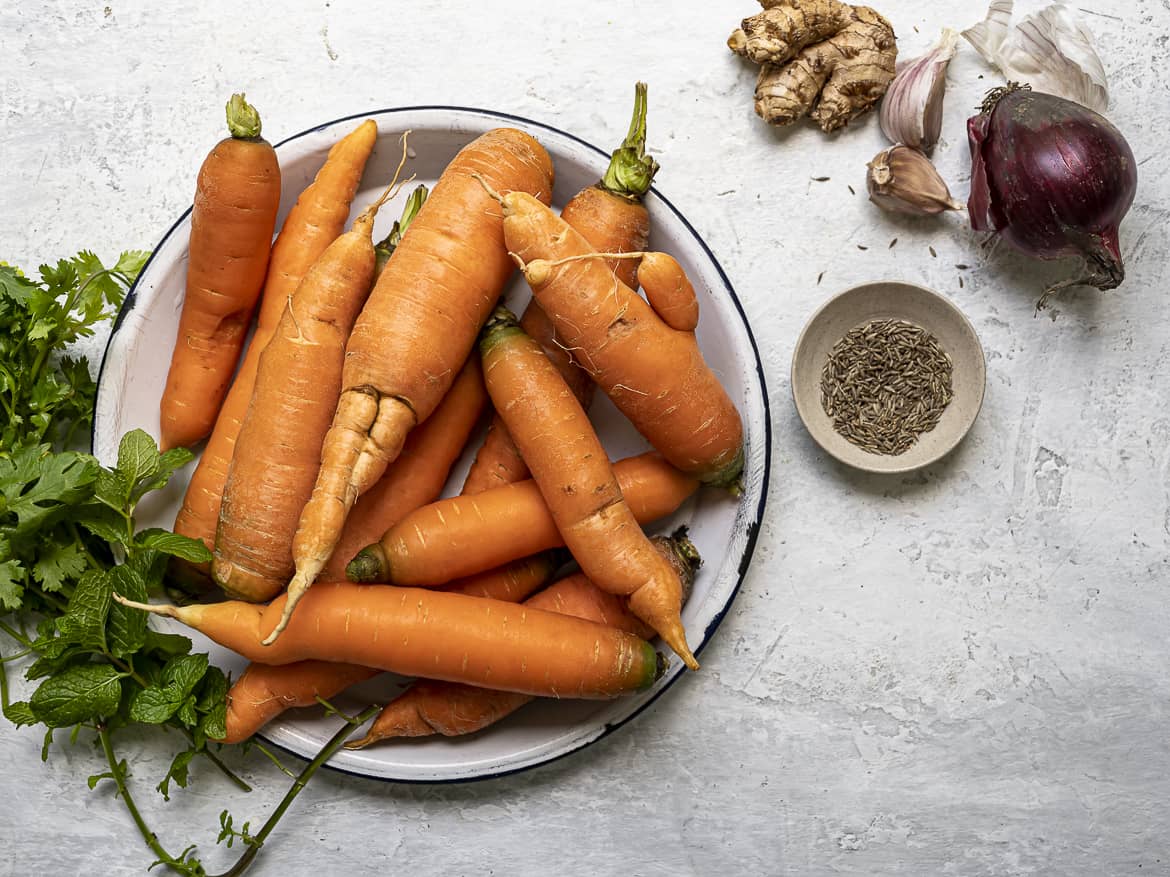 Raw carrots in bowl with soup ingredients