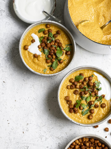 serving bowls with roasted carrot soup topped with crispy chickpeas