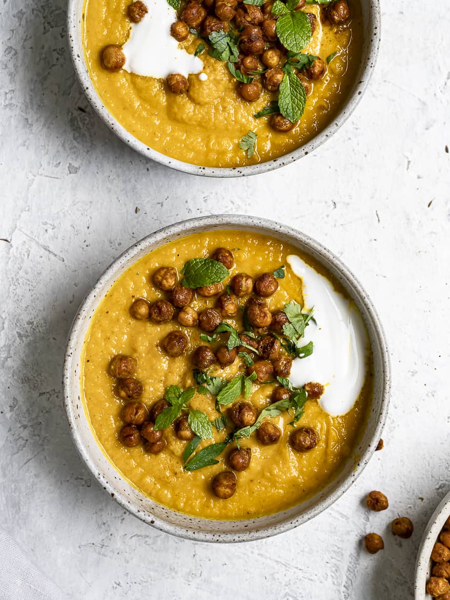 Bowls with roasted carrot soup topped with crispy chickpeas