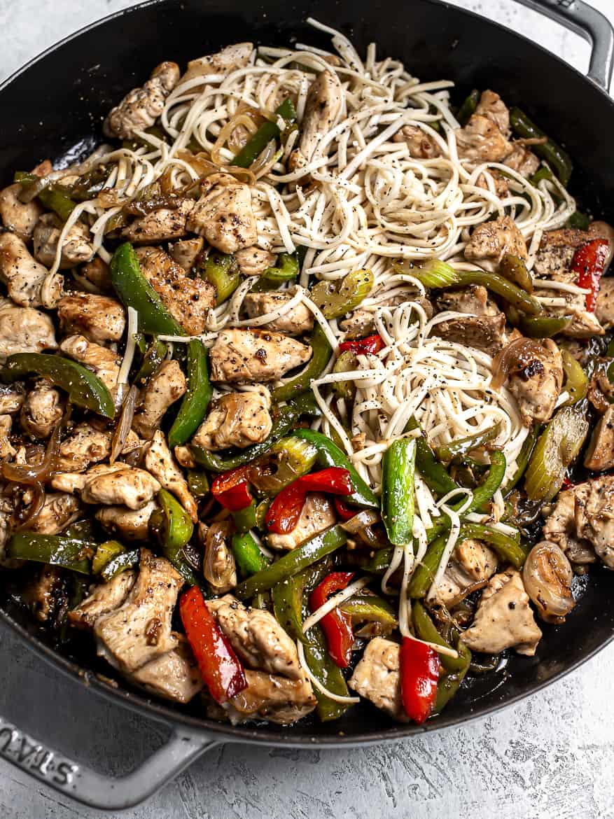 Chicken in skillet with green peppers onions and noodles