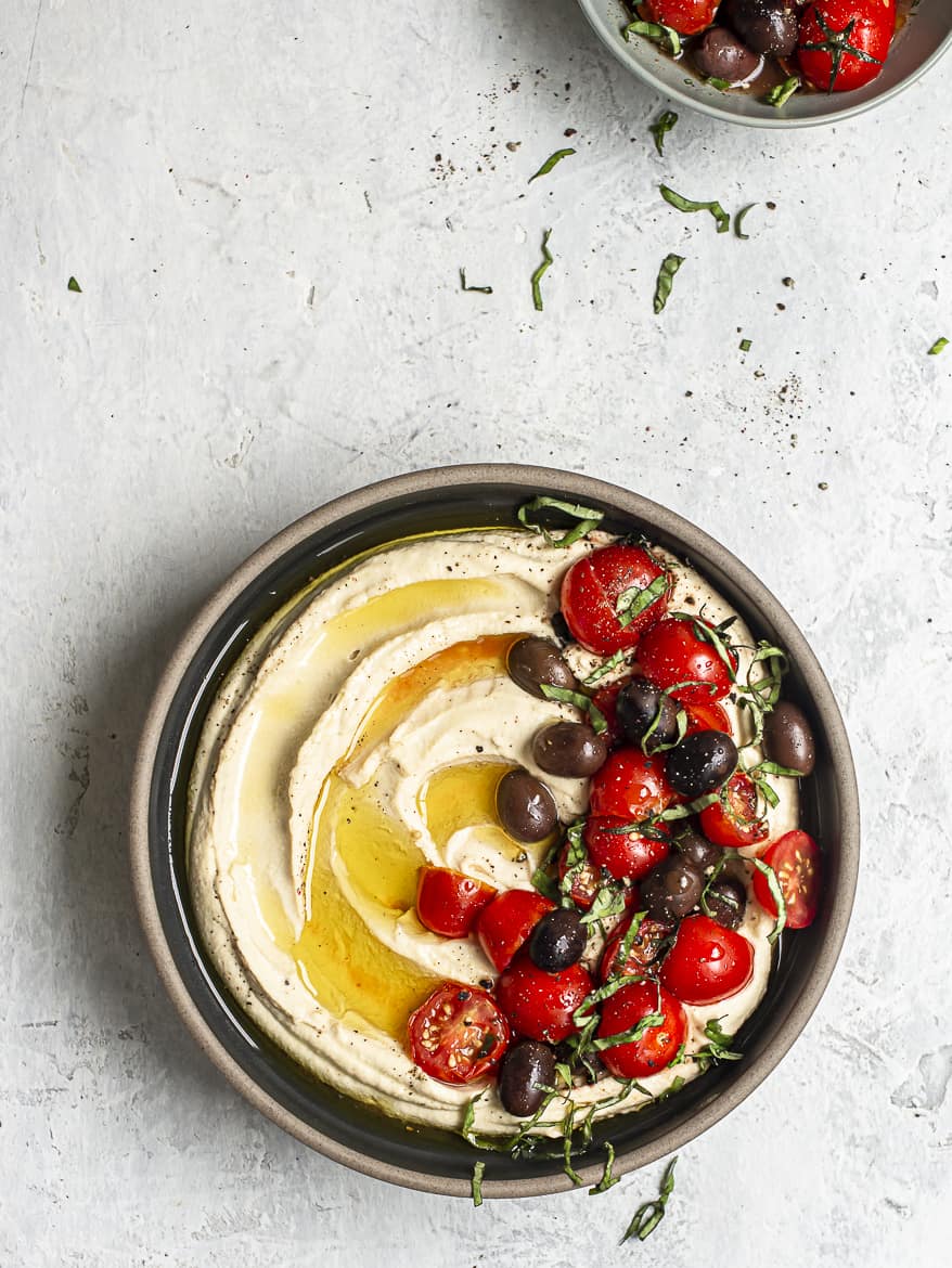 Ultra Smooth Hummus in bowl topped with marinated tomatoes and olives