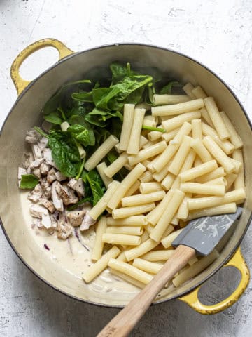 Adding pasta and spinach to hummus sauce