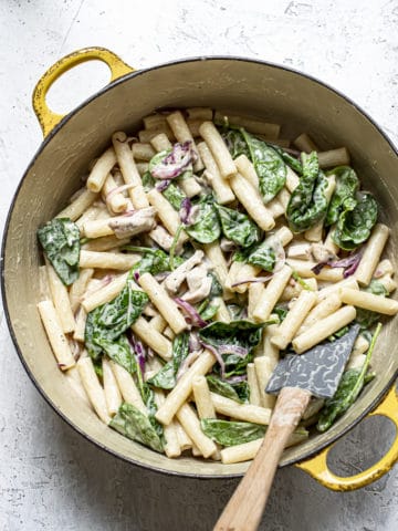 Mixing pasta and spinach with hummus sauce