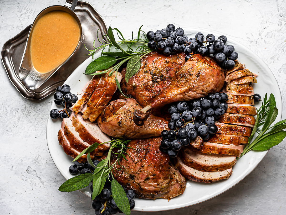 Spatchcock Turkey with dry brine on platter with gravy on the side.