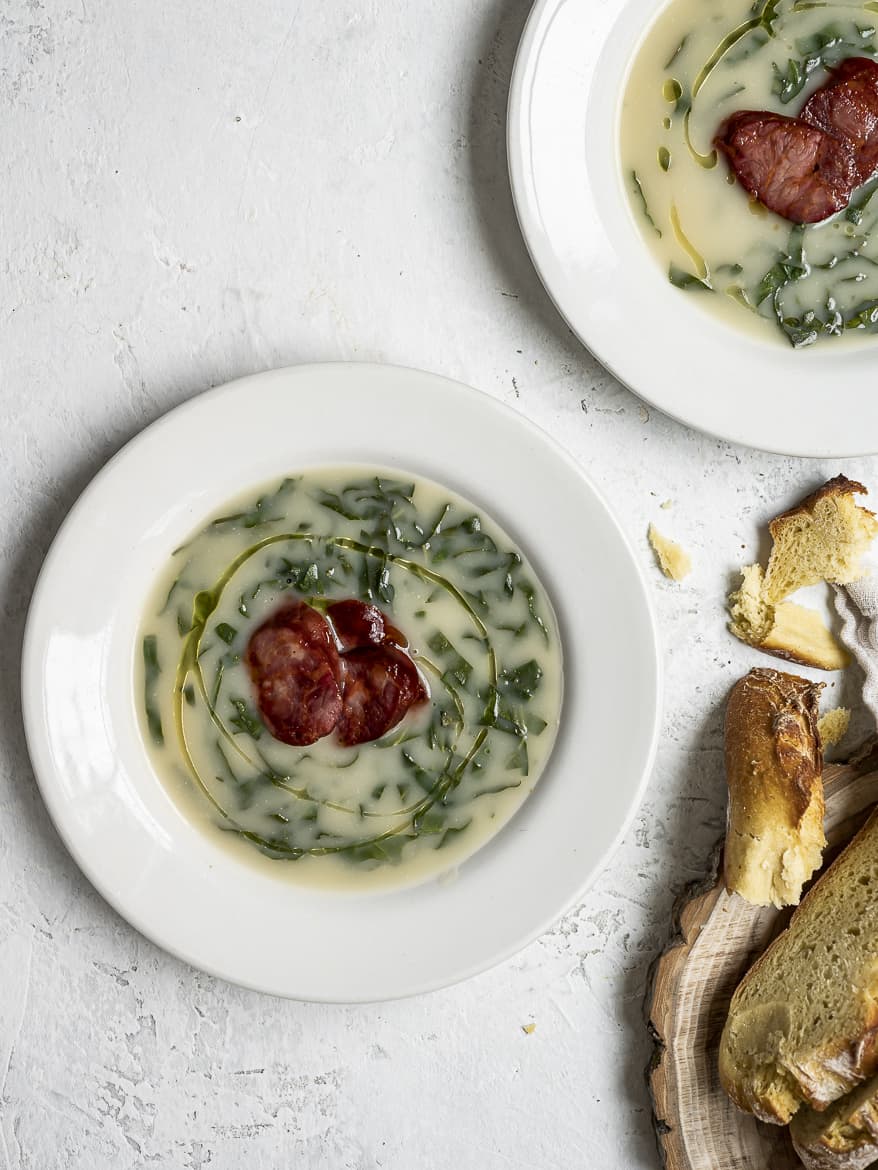 Caldo verde in bowls topped with choriço sausage and bread chunks on the side 