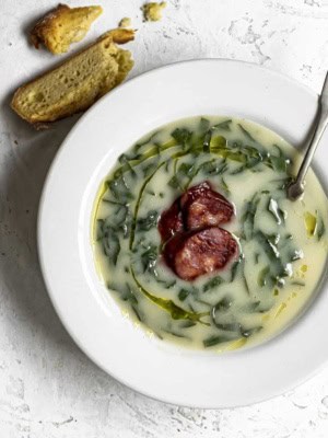 Close up of Caldo verde in soup bowl with chunks of Portuguese corn bread on the side