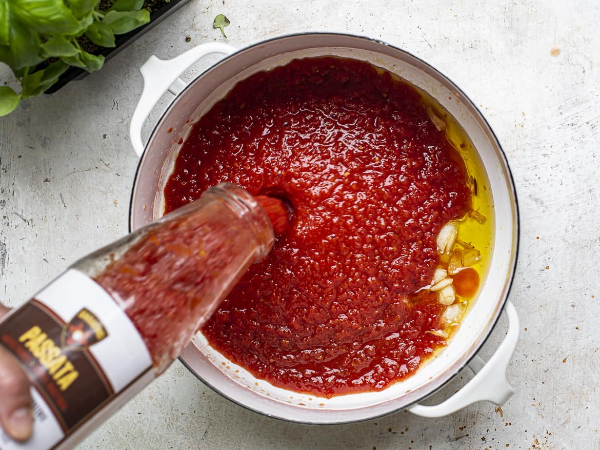 pouring tomato sauce in pot