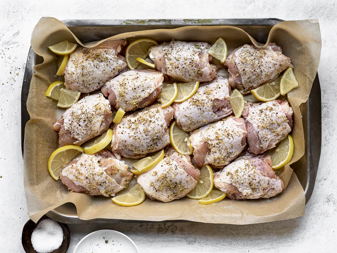chicken thighs with lemon slices ready to bake