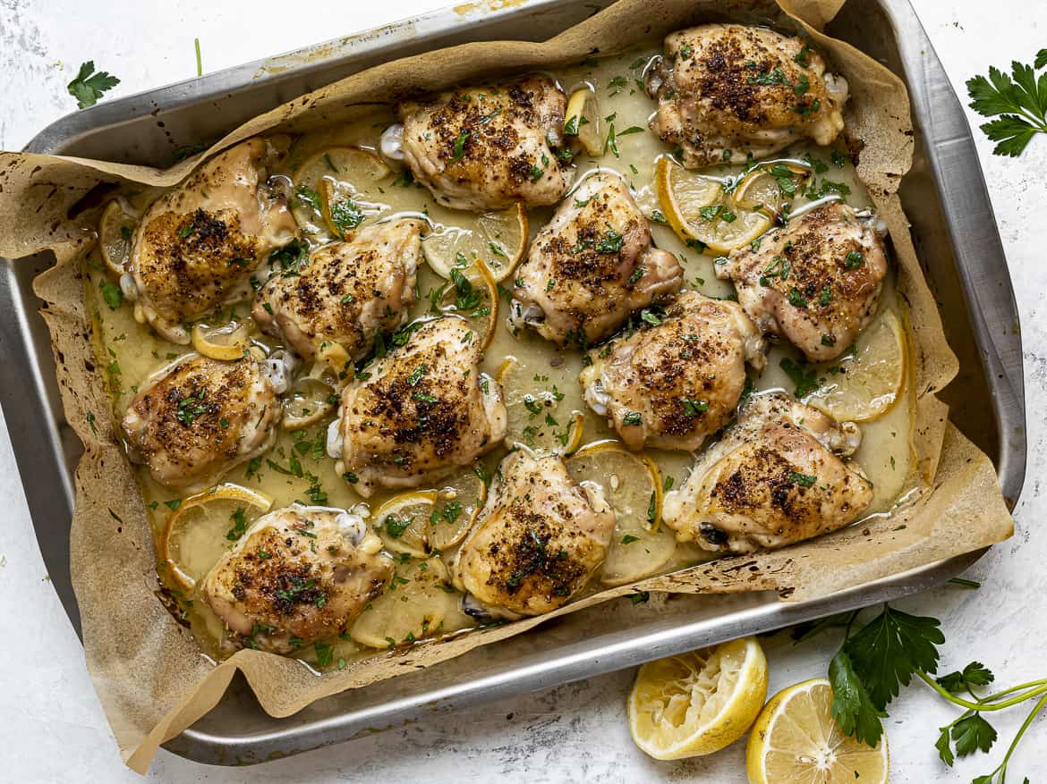 close up of baked lemon chicken thighs in baking pan