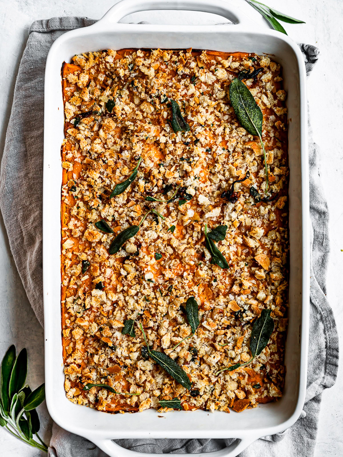 baked savory sweet potato casserole garnished with sage leaves