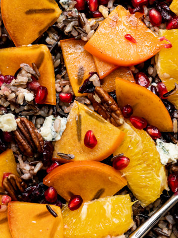 Close up of Mixing wild rice salad with persimmons